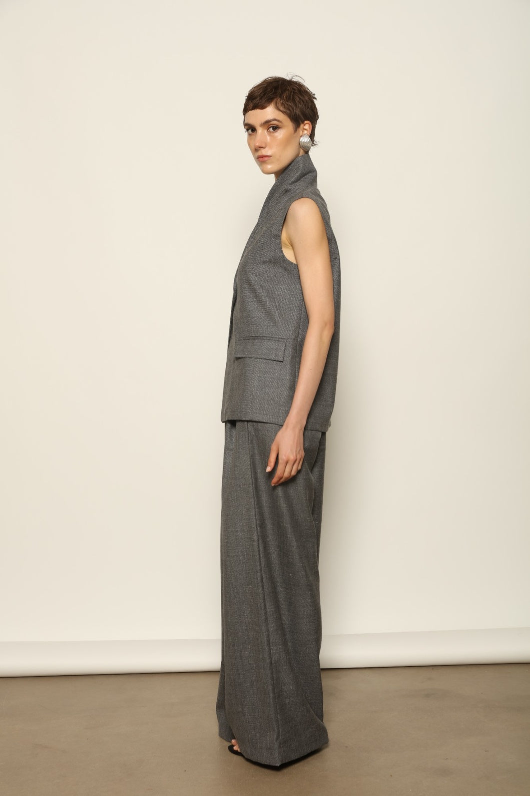 Grey Off-White Parigi Trousers by House of Nomad Stories, featuring a relaxed tailored silhouette, fluid lines, breathable Italian fabric, and an understated grey off-white tone.