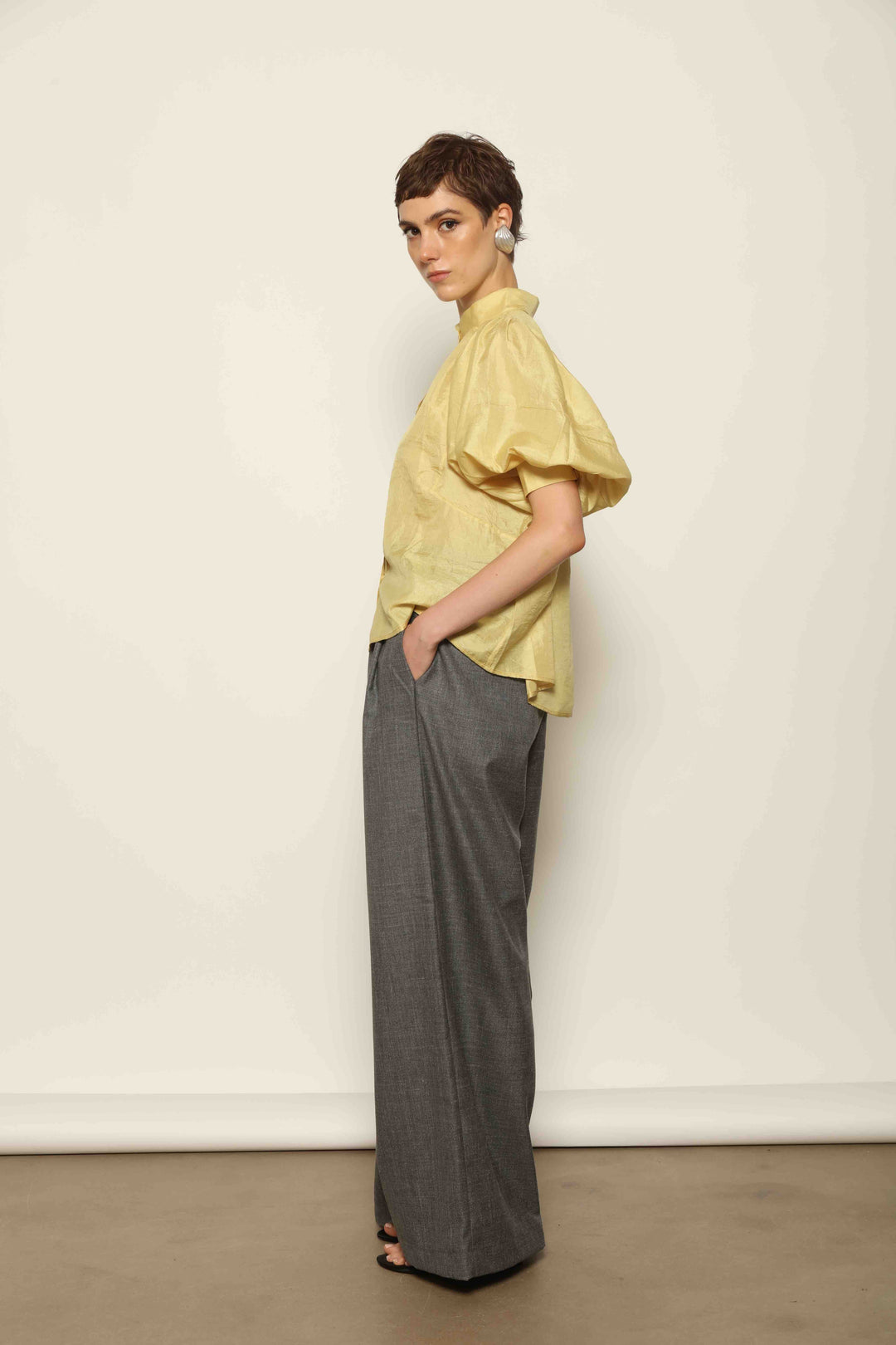 Grey Off-White Parigi Trousers by House of Nomad Stories, featuring a relaxed tailored silhouette, fluid lines, breathable Italian fabric, and an understated grey off-white tone.