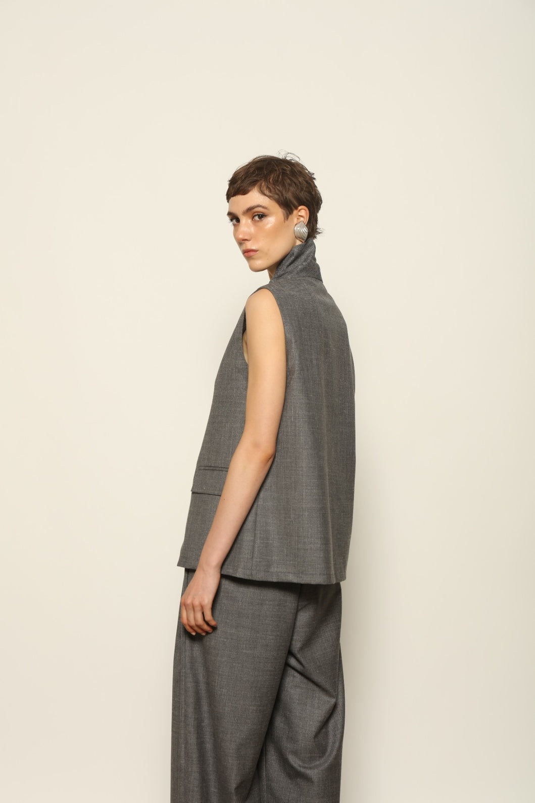 Grey Off-White Parigi Trousers by House of Nomad Stories, featuring a relaxed tailored silhouette, fluid lines, breathable Italian fabric, and an understated grey off-white tone.