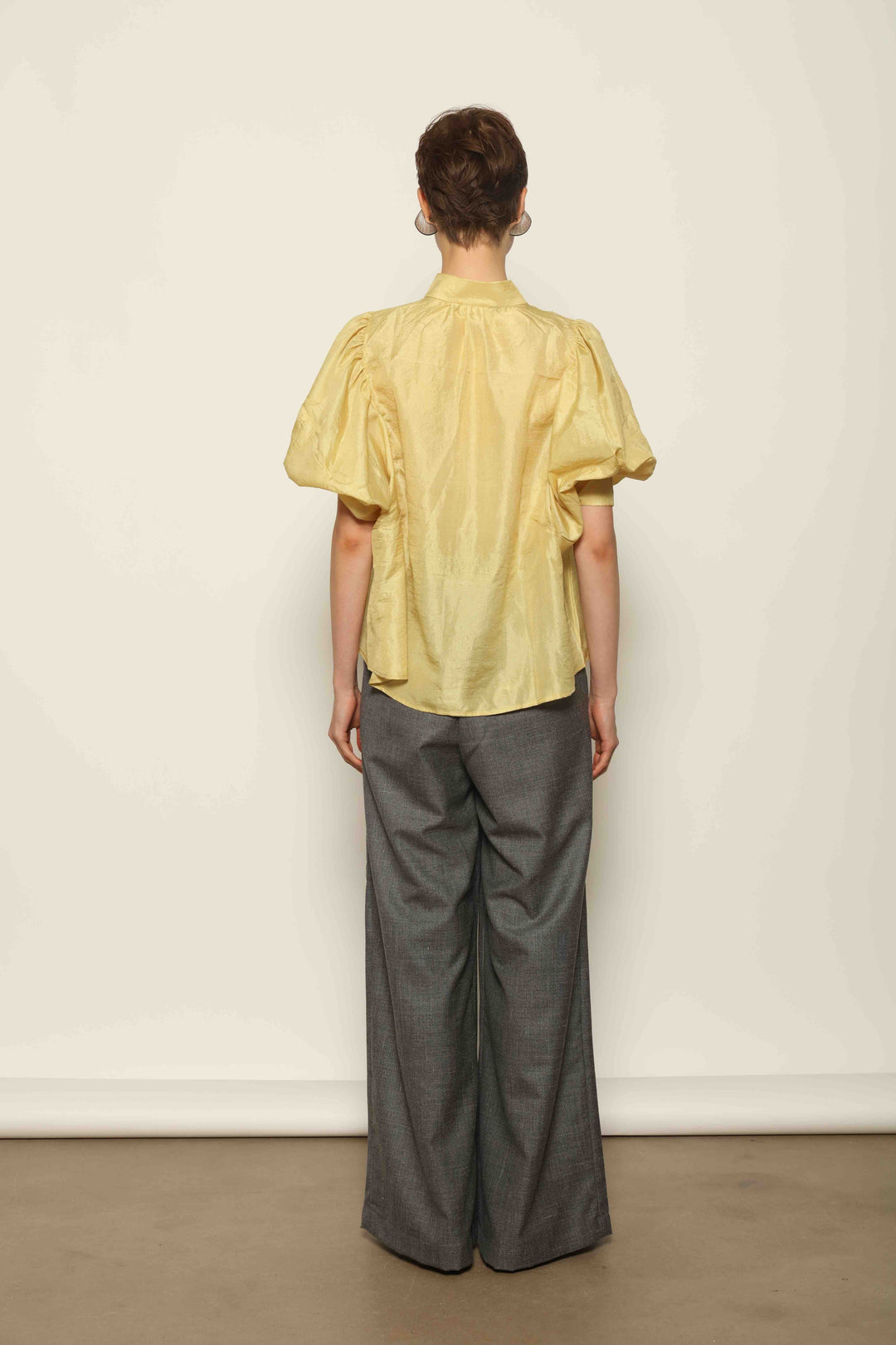 Grey Off-White Parigi Trousers by House of Nomad Stories, featuring a relaxed tailored silhouette, fluid lines, breathable Italian fabric, and an understated grey off-white tone.