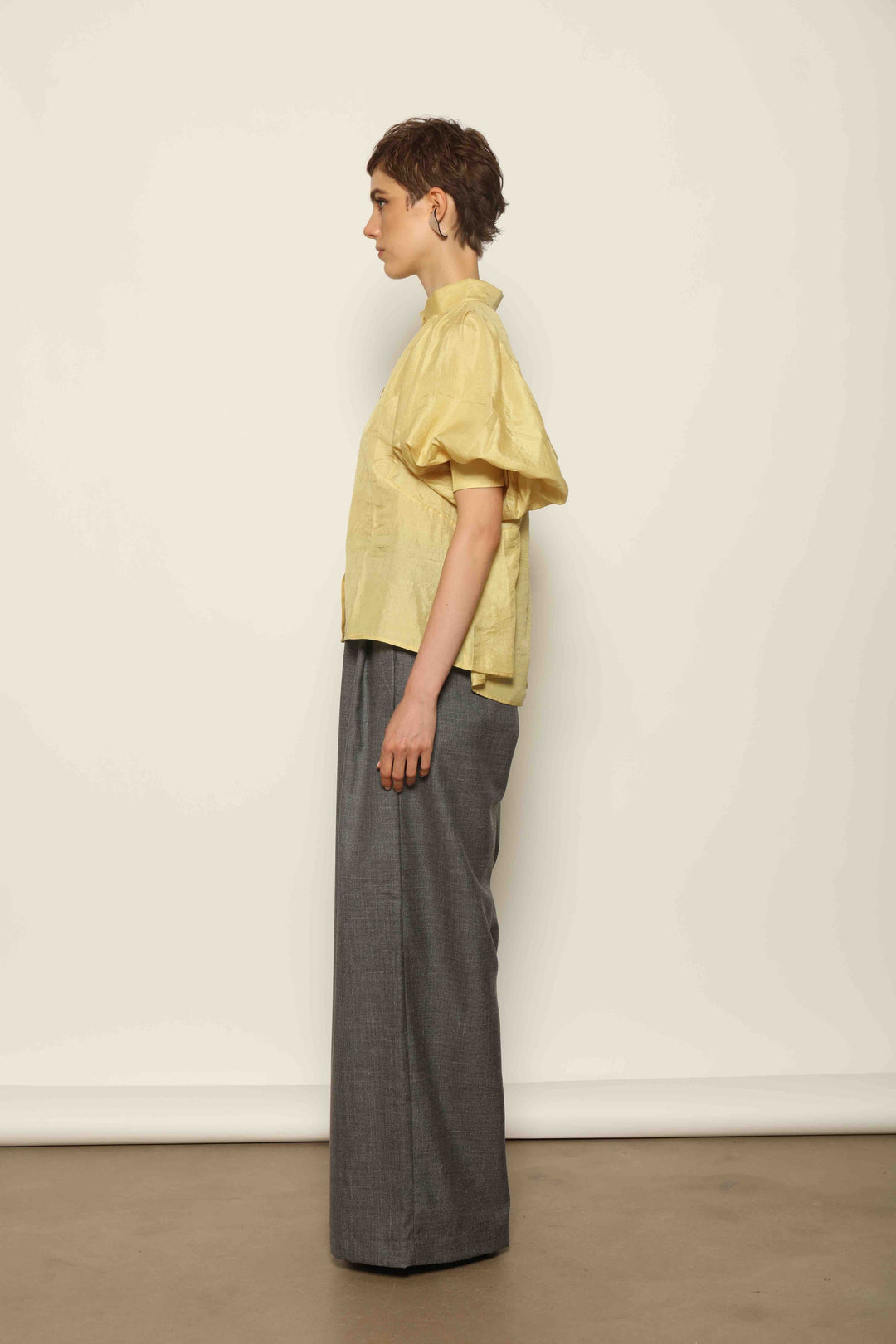 Grey Off-White Parigi Trousers by House of Nomad Stories, featuring a relaxed tailored silhouette, fluid lines, breathable Italian fabric, and an understated grey off-white tone.