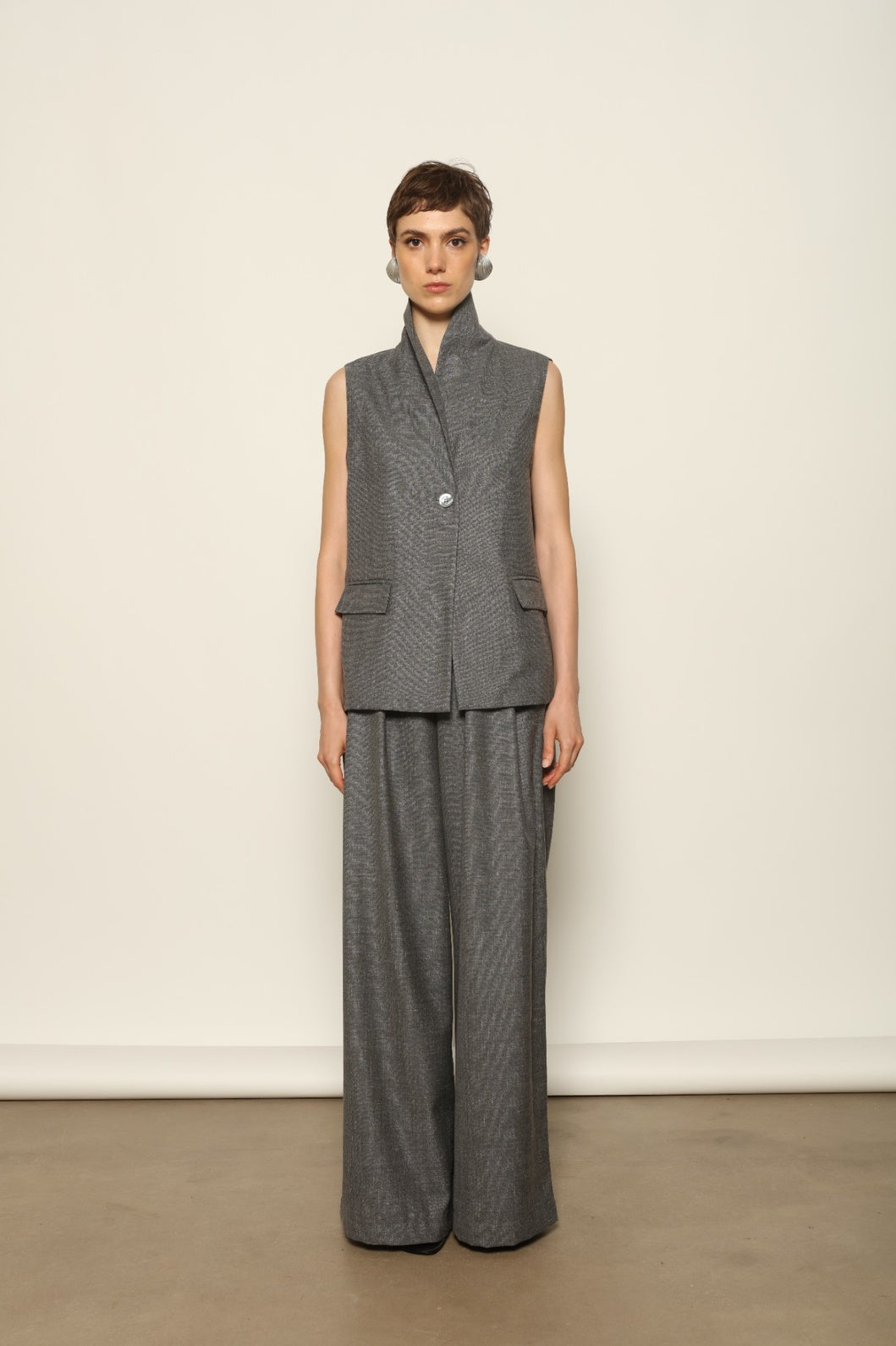 Grey Off-White Parigi Trousers by House of Nomad Stories, featuring a relaxed tailored silhouette, fluid lines, breathable Italian fabric, and an understated grey off-white tone.