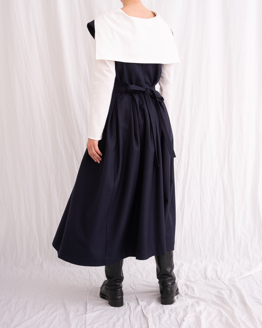 Model is wearing the Sarafan Pure New Wool Dress by Les Vacances d’Irina, a handmade navy merino wool dress with A-line silhouette, tie-back detail, horn buttons, and side pockets, available at House of Nomad Stories.