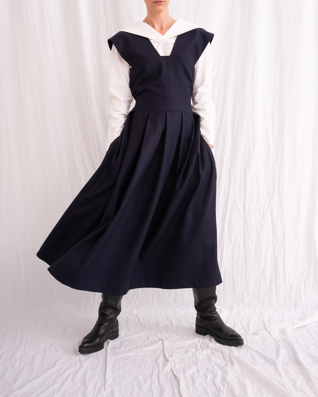 Model is wearing the Sarafan Pure New Wool Dress by Les Vacances d’Irina, a handmade navy merino wool dress with A-line silhouette, tie-back detail, horn buttons, and side pockets, available at House of Nomad Stories.