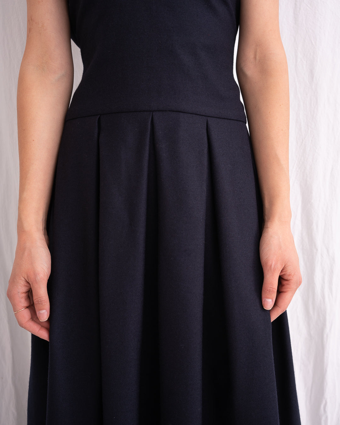 Model is wearing the Sarafan Pure New Wool Dress by Les Vacances d’Irina, a handmade navy merino wool dress with A-line silhouette, tie-back detail, horn buttons, and side pockets, available at House of Nomad Stories.