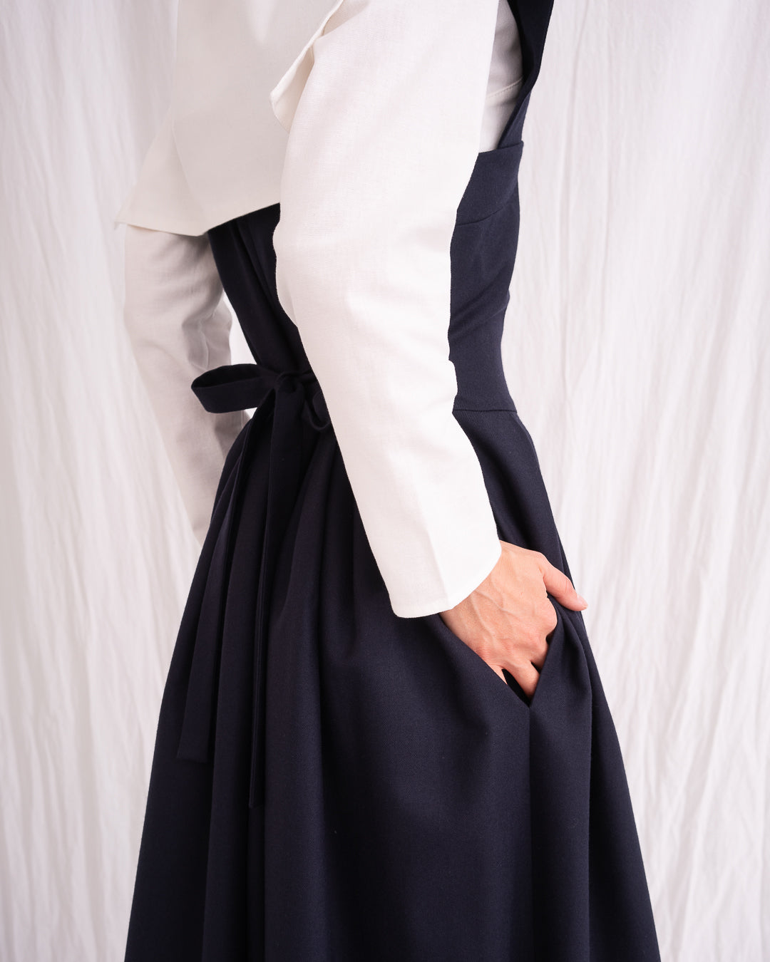Model is wearing the Sarafan Pure New Wool Dress by Les Vacances d’Irina, a handmade navy merino wool dress with A-line silhouette, tie-back detail, horn buttons, and side pockets, available at House of Nomad Stories.
