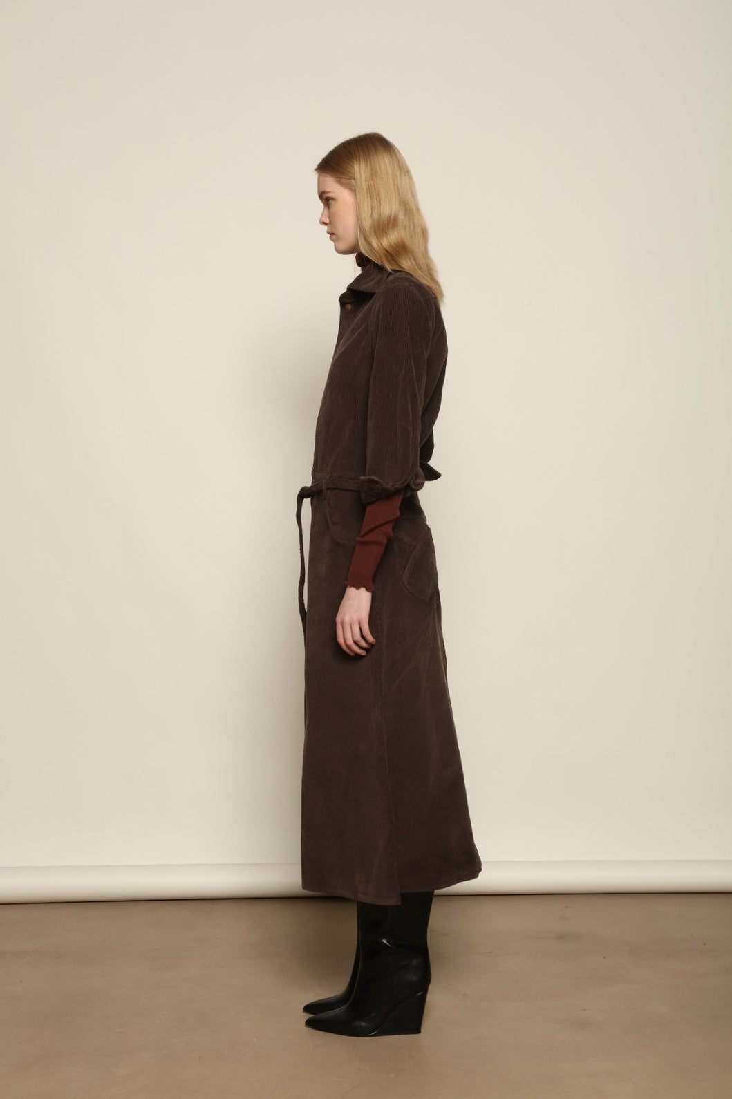 Model is wearing La Robe Trompe L’Oeil in Chocolate by Happy Haus, a corduroy cotton trompe-l’œil dress with removable belt, tulip-shaped pockets and brass snaps, curated in the House of Nomad Stories selection.