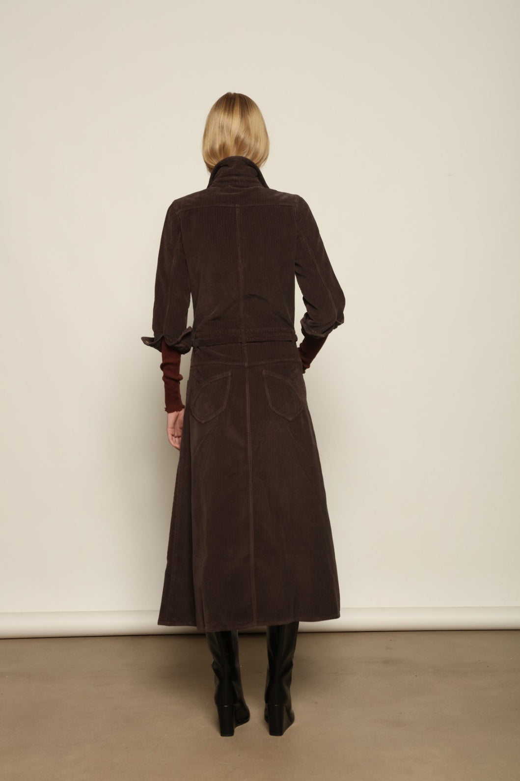 Model is wearing La Robe Trompe L’Oeil in Chocolate by Happy Haus, a corduroy cotton trompe-l’œil dress with removable belt, tulip-shaped pockets and brass snaps, curated in the House of Nomad Stories selection.