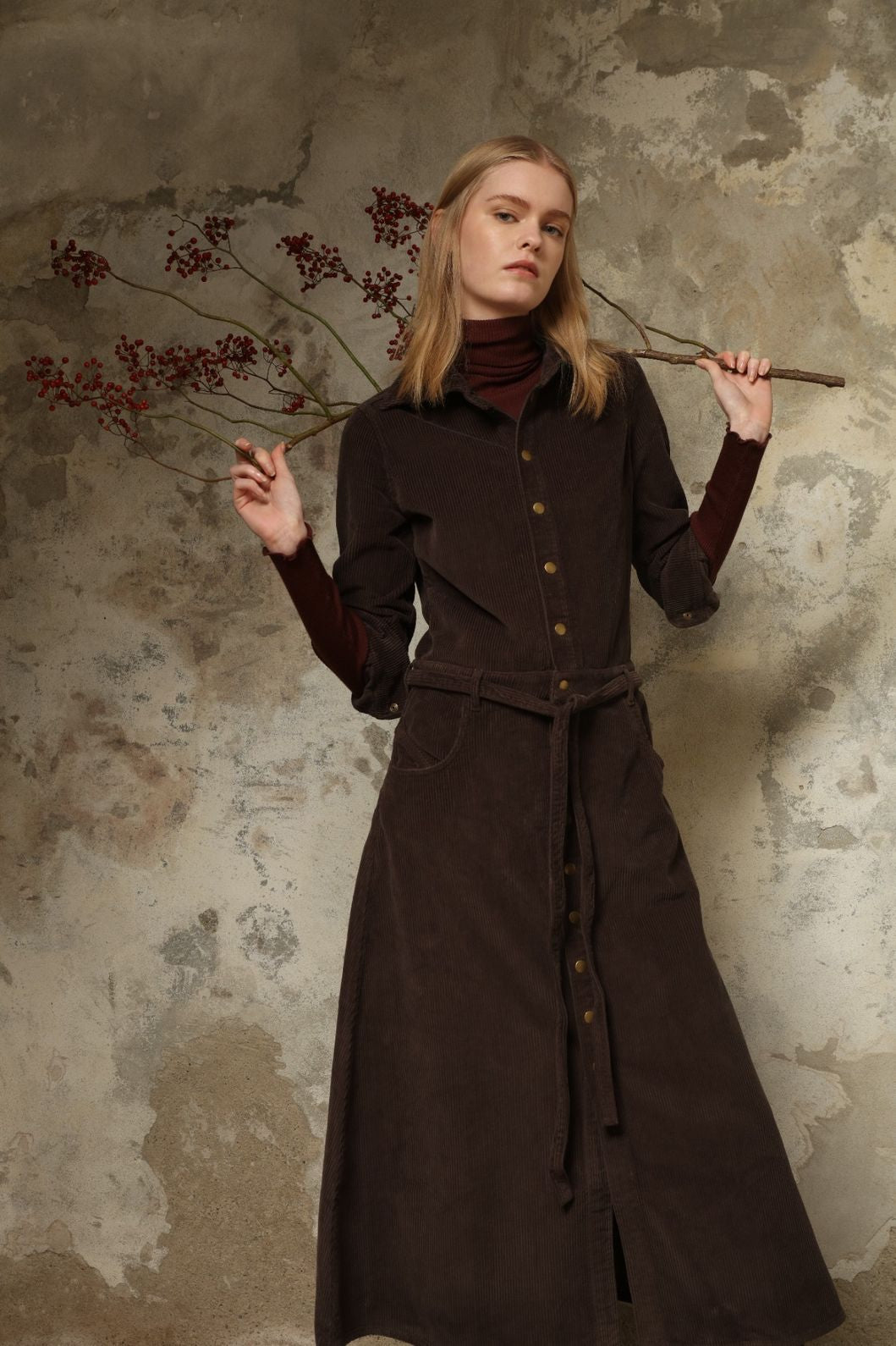 Model is wearing La Robe Trompe L’Oeil in Chocolate by Happy Haus, a corduroy cotton trompe-l’œil dress with removable belt, tulip-shaped pockets and brass snaps, curated in the House of Nomad Stories selection.