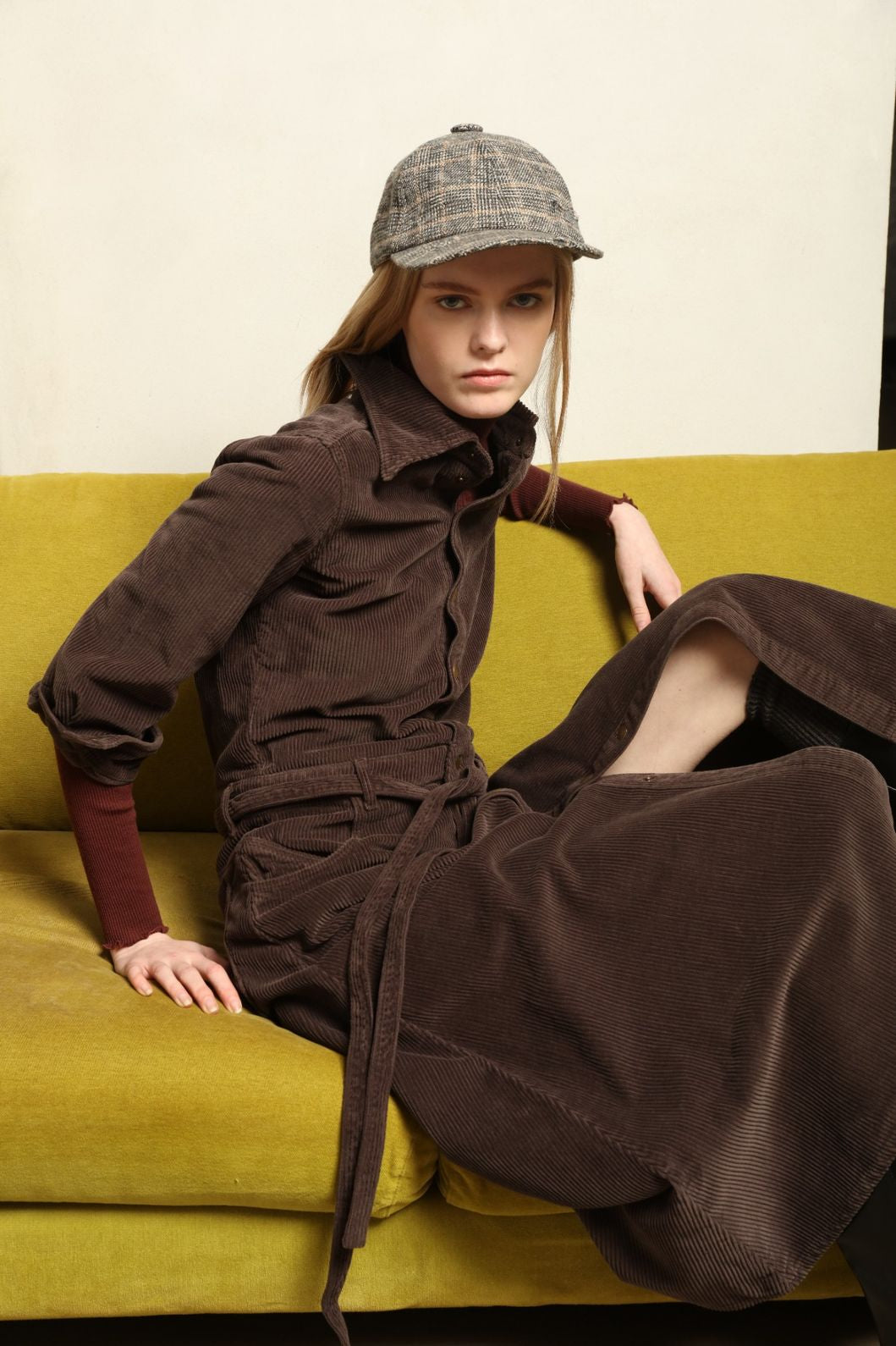 Model is wearing La Robe Trompe L’Oeil in Chocolate by Happy Haus, a corduroy cotton trompe-l’œil dress with removable belt, tulip-shaped pockets and brass snaps, curated in the House of Nomad Stories selection.