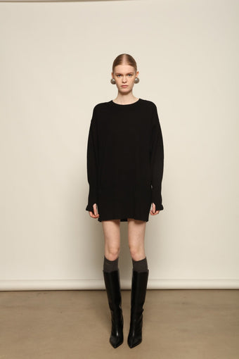 Model is wearing the Black Noemi Round Neck Long Sweater by House of Nomad Stories, a pure ethically sourced cashmere knit in deep black with long silhouette, round neckline and ribbed edges.