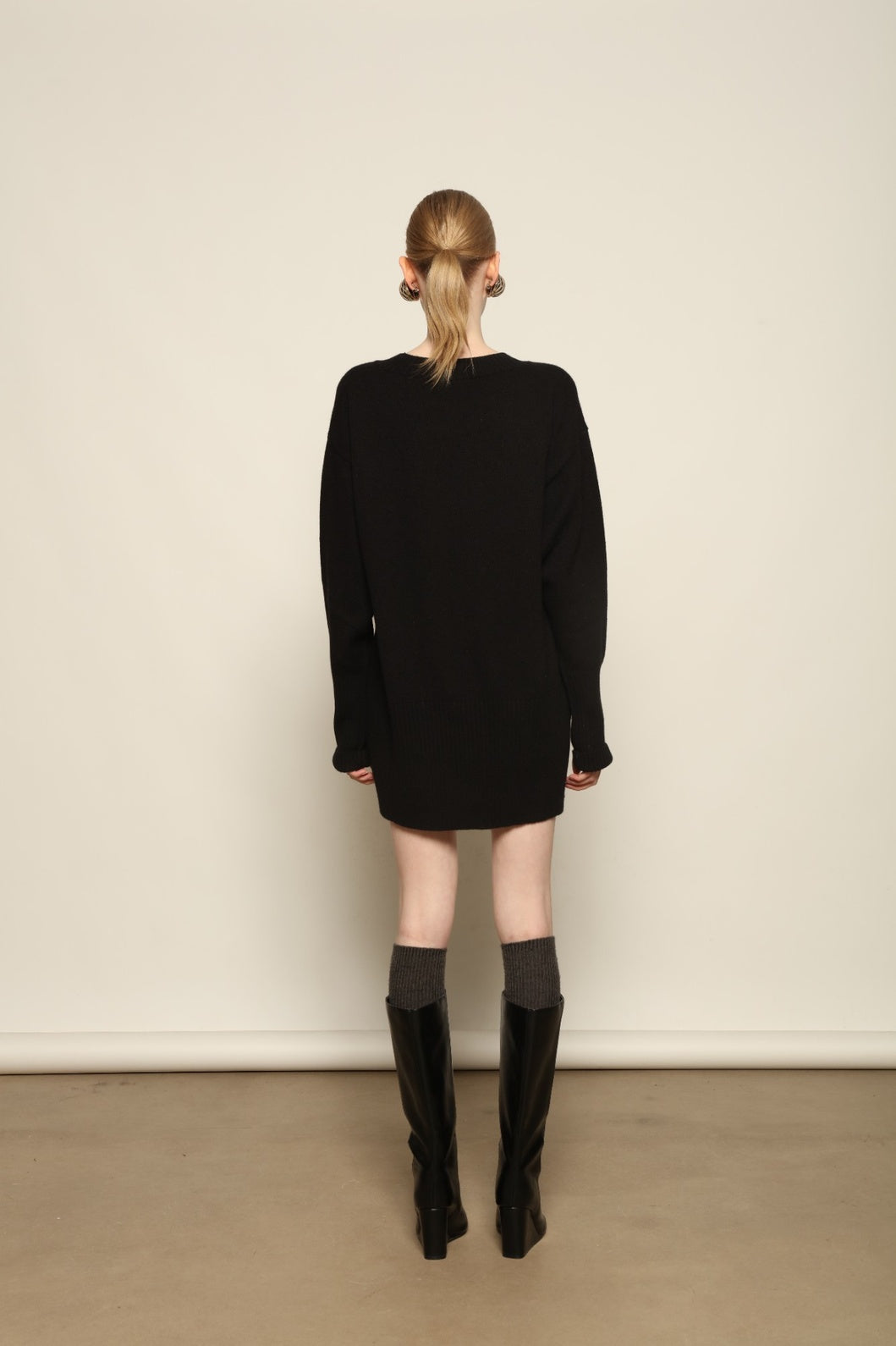 Model is wearing the Black Noemi Round Neck Long Sweater by House of Nomad Stories, a pure ethically sourced cashmere knit in deep black with long silhouette, round neckline and ribbed edges.