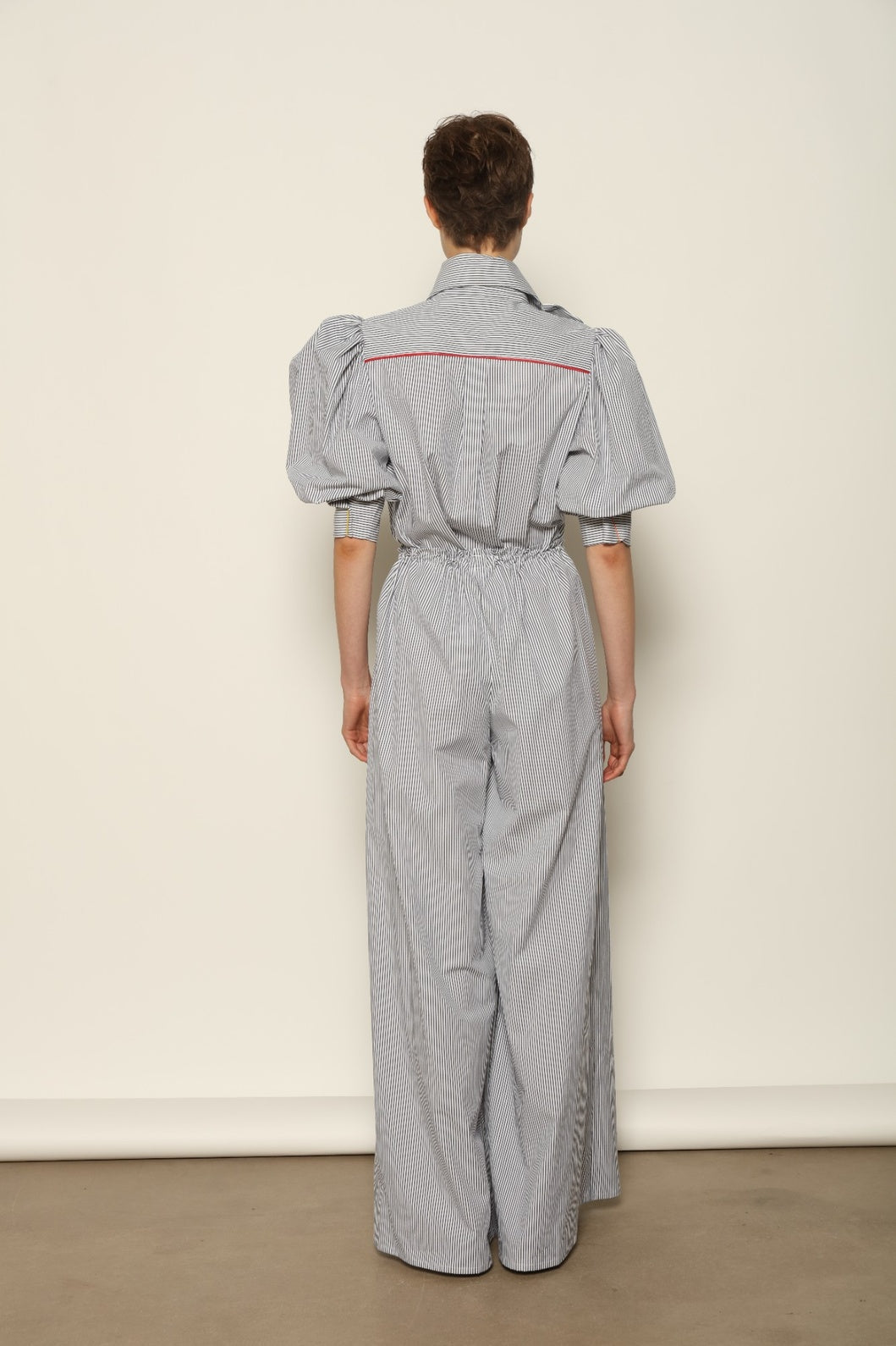 Model wearing the Brigitta White Navy Striped Trousers by House of Nomad Stories, featuring 100% organic cotton fabric, high-rise waist, wide-leg silhouette, and classic white and navy stripes.