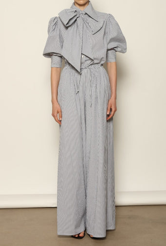 Model wearing the Brigitta White Navy Striped Trousers by House of Nomad Stories, featuring 100% organic cotton fabric, high-rise waist, wide-leg silhouette, and classic white and navy stripes.
