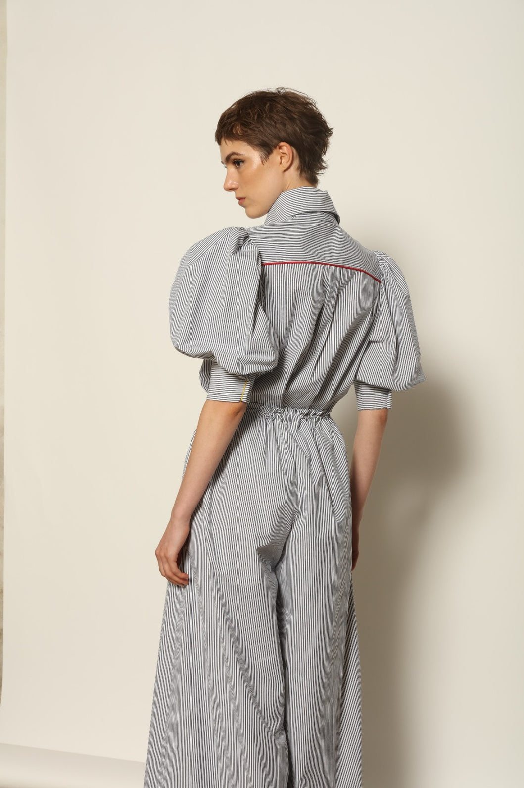 Model wearing the Brigitta White Navy Striped Trousers by House of Nomad Stories, featuring 100% organic cotton fabric, high-rise waist, wide-leg silhouette, and classic white and navy stripes.