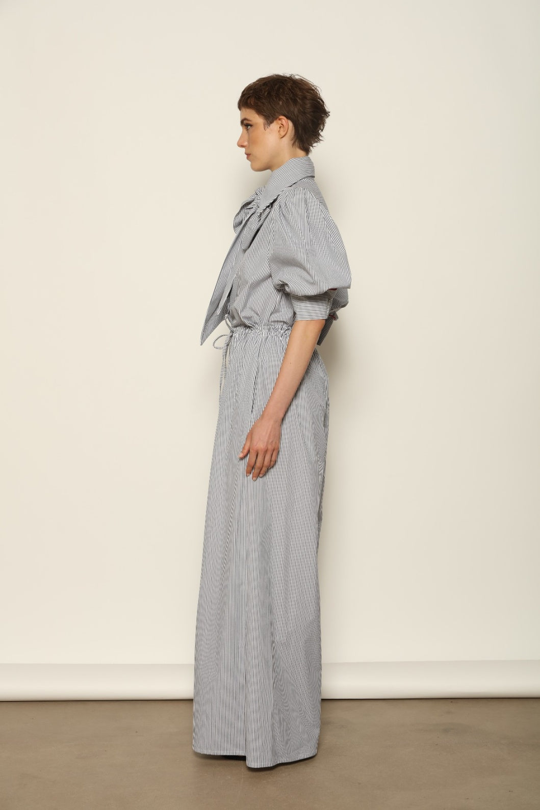 Model wearing the Brigitta White Navy Striped Trousers by House of Nomad Stories, featuring 100% organic cotton fabric, high-rise waist, wide-leg silhouette, and classic white and navy stripes.