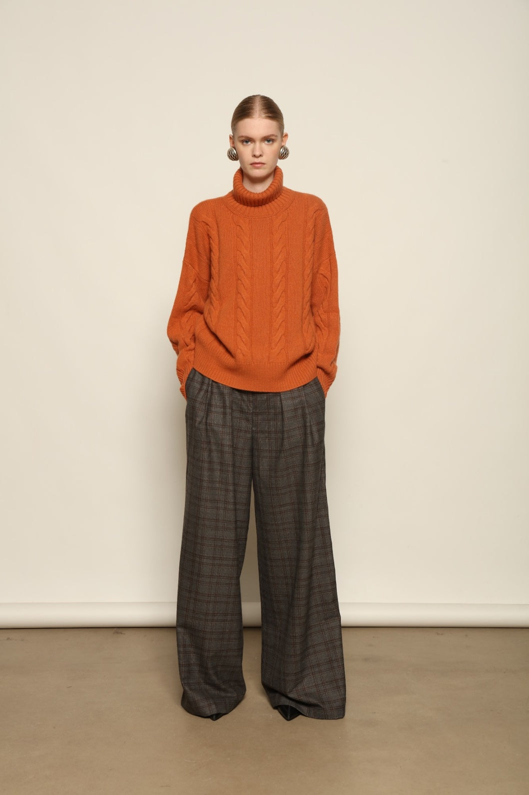 Model is wearing the Brown Check Parigi Pants by House of Nomad Stories, relaxed straight-leg Merino wool trousers with a soft brown check pattern, handcrafted in Italy.