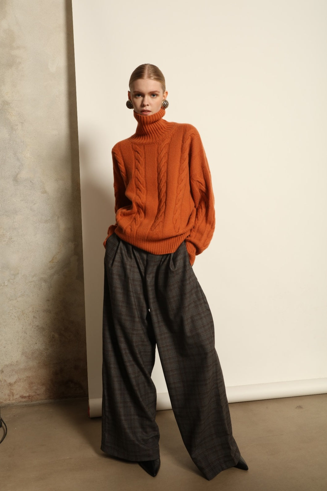 Model is wearing the Brown Check Parigi Pants by House of Nomad Stories, relaxed straight-leg Merino wool trousers with a soft brown check pattern, handcrafted in Italy.