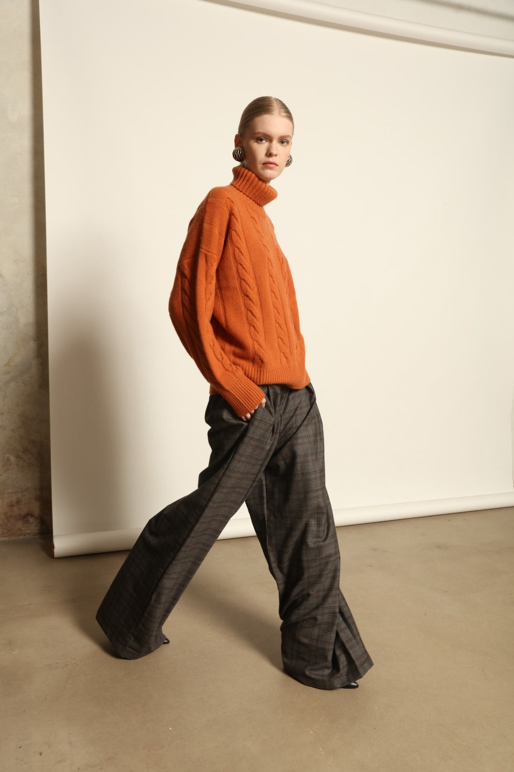Model is wearing the Brown Check Parigi Pants by House of Nomad Stories, relaxed straight-leg Merino wool trousers with a soft brown check pattern, handcrafted in Italy.