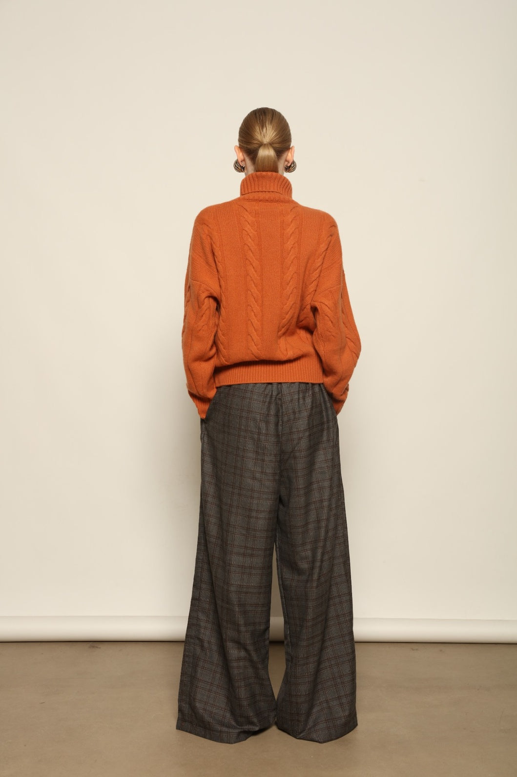 Model is wearing the Brown Check Parigi Pants by House of Nomad Stories, relaxed straight-leg Merino wool trousers with a soft brown check pattern, handcrafted in Italy.