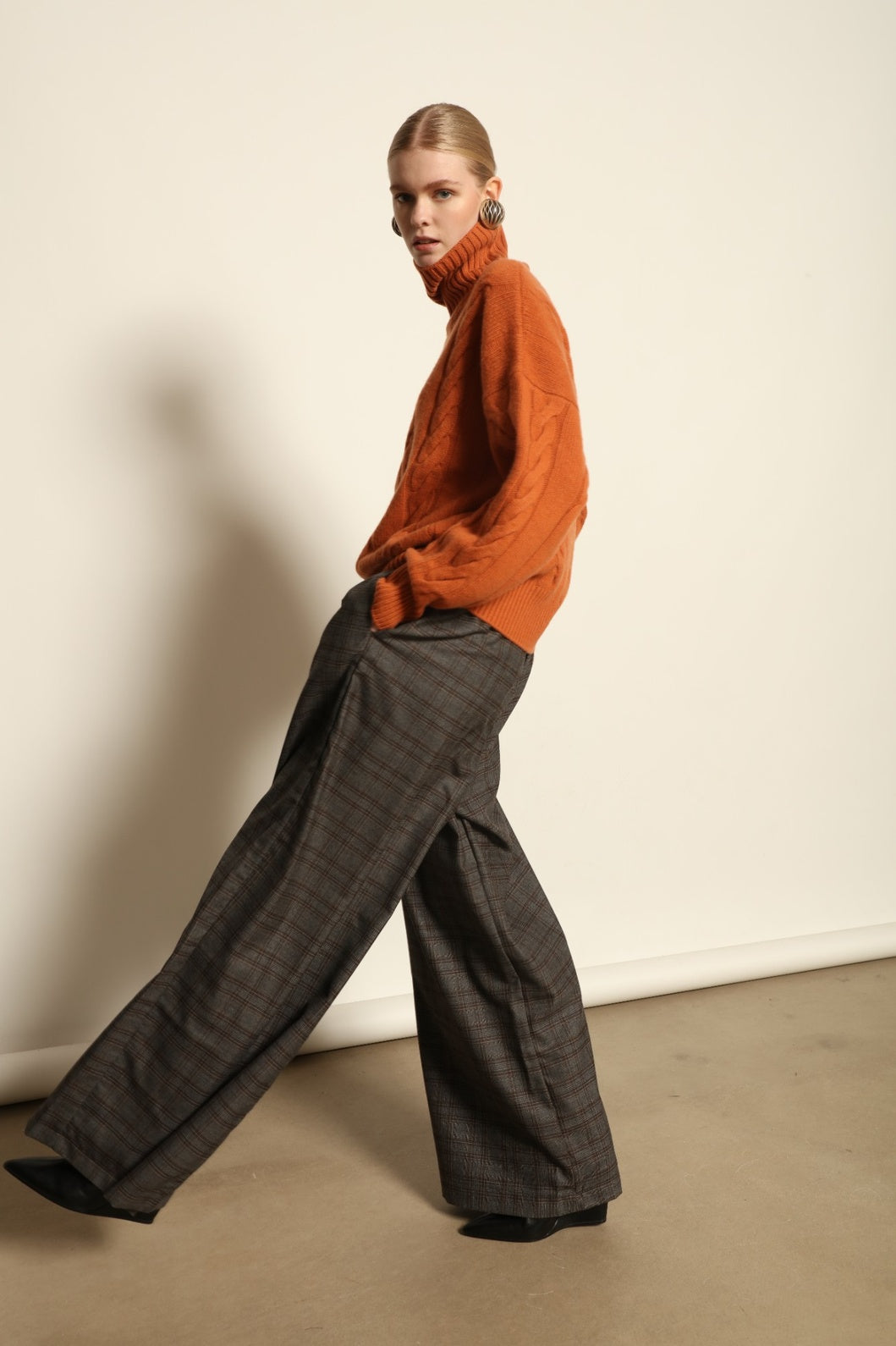 Model is wearing the Brown Check Parigi Pants by House of Nomad Stories, relaxed straight-leg Merino wool trousers with a soft brown check pattern, handcrafted in Italy.