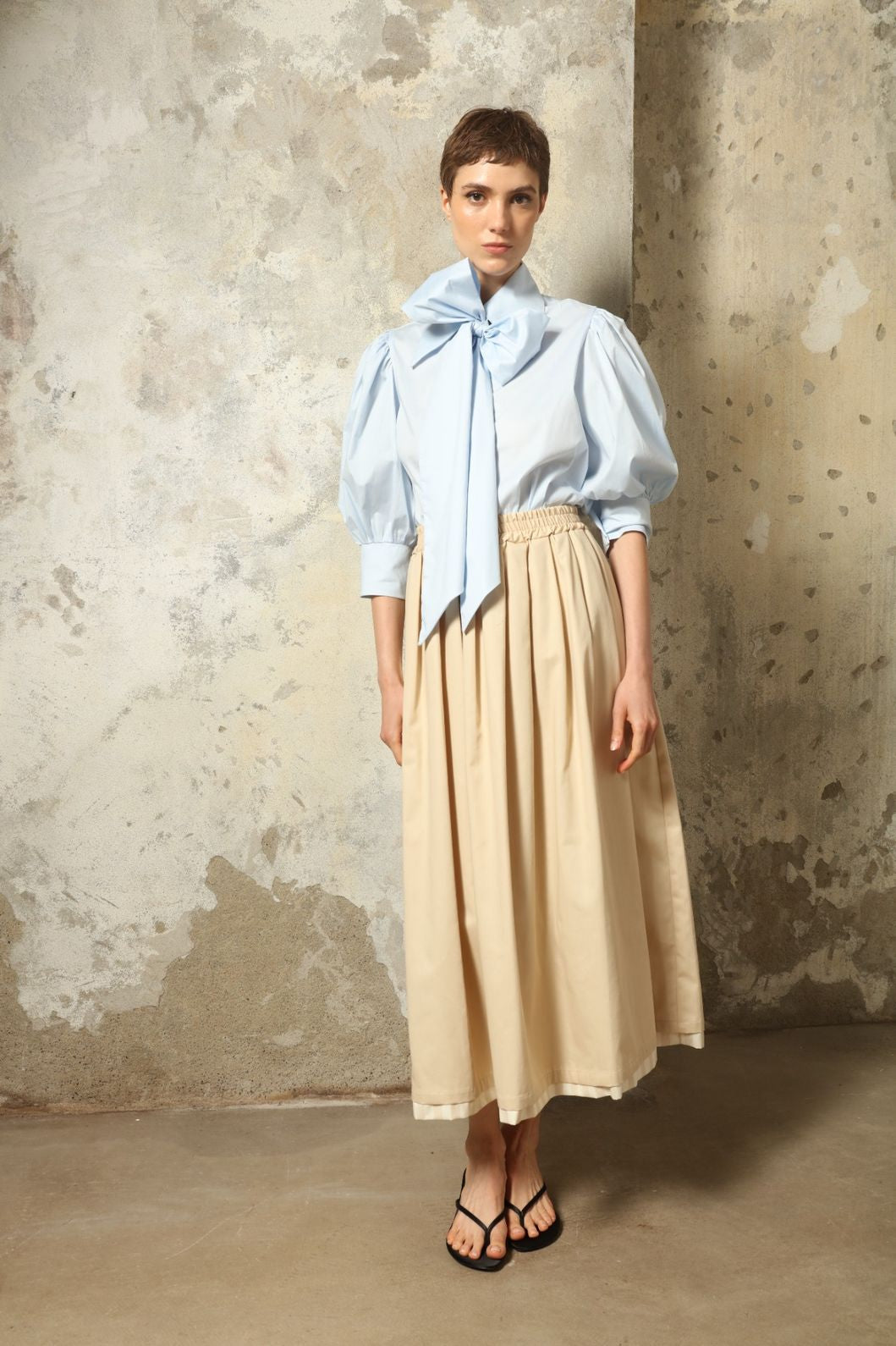 Model wearing the Seoul Camel Skirt by House of Nomad Stories, featuring a structured camel-toned fabric, high-waisted fit, and a clean tailored silhouette with defined architectural lines.