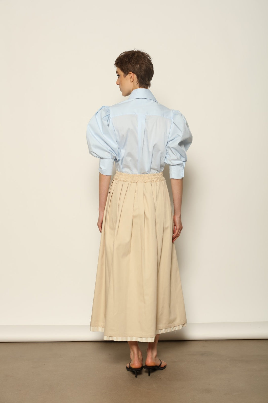 Model wearing the Seoul Camel Skirt by House of Nomad Stories, featuring a structured camel-toned fabric, high-waisted fit, and a clean tailored silhouette with defined architectural lines.