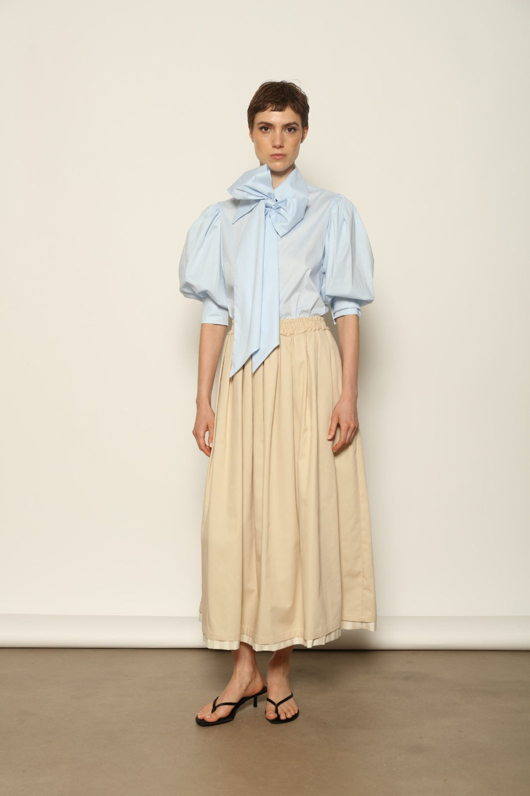 Model wearing the Seoul Camel Skirt by House of Nomad Stories, featuring a structured camel-toned fabric, high-waisted fit, and a clean tailored silhouette with defined architectural lines.