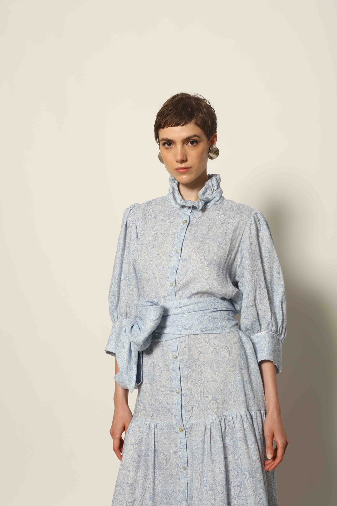 Model wearing the Karin Blue Paisley Dress by House of Nomad Stories, featuring 100% linen fabric, soft blue paisley print, and a relaxed flowing silhouette with breathable lightweight structure.