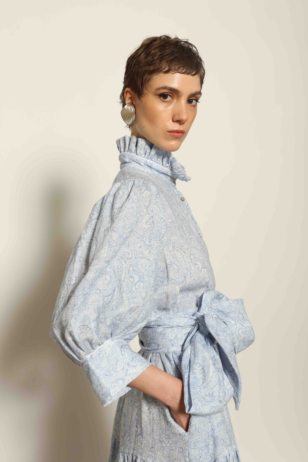 Model wearing the Karin Blue Paisley Dress by House of Nomad Stories, featuring 100% linen fabric, soft blue paisley print, and a relaxed flowing silhouette with breathable lightweight structure.