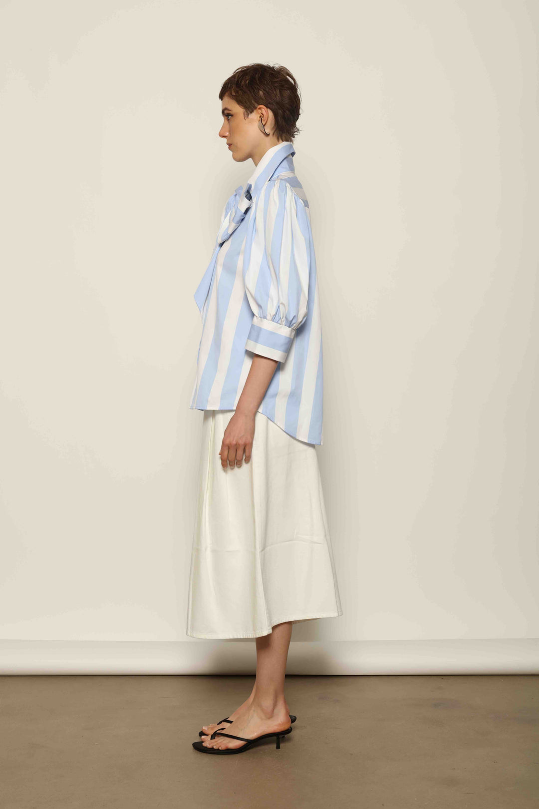 Model wearing the Karin Blue and White Macro Striped Blouse by House of Woven Stories, featuring bold macro stripes, relaxed fit silhouette, and lightweight 100% organic cotton fabric made in Italy.