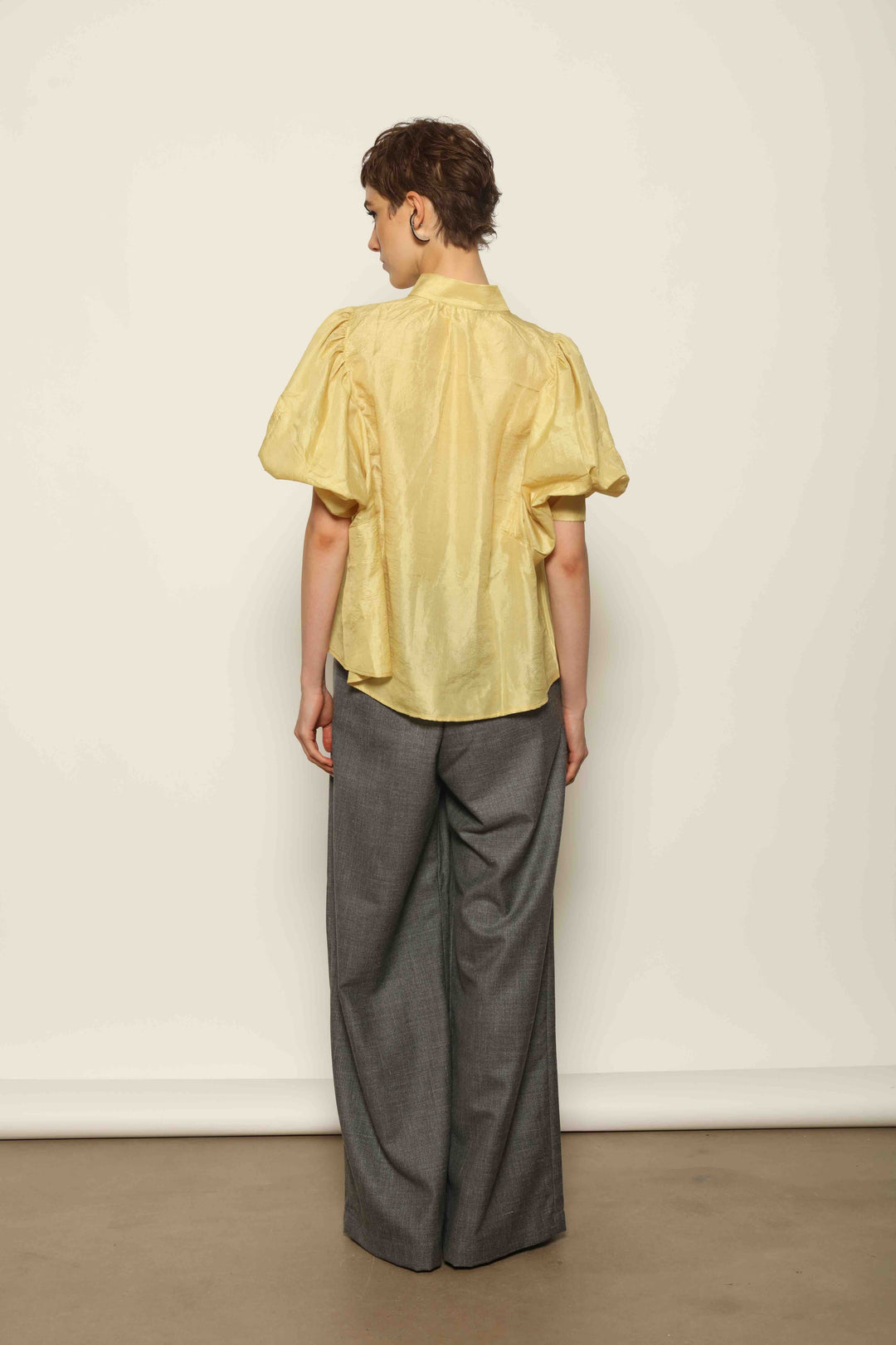 Model wearing the Lola Yellow Blouse by House of Woven Stories, crafted from naturally dyed Mulberry silk with a Mandarin collar, button-front closure, and short balloon sleeves with fitted cuffs.