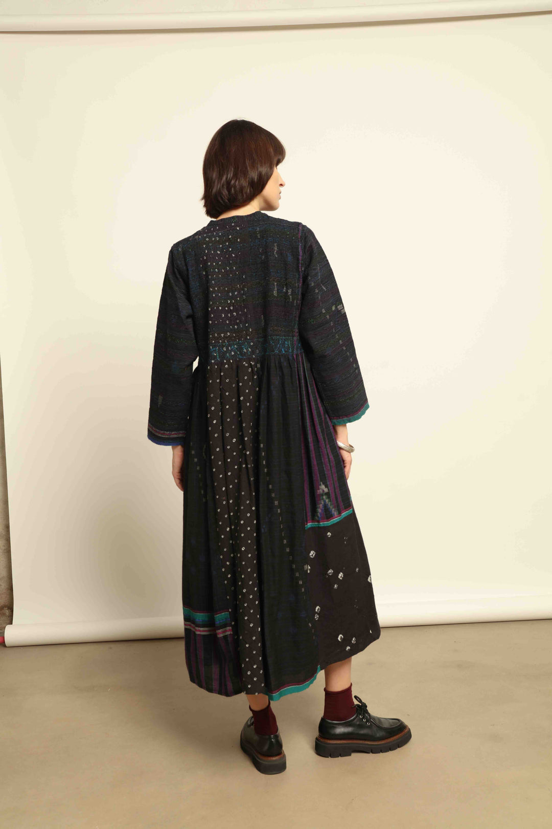 Model is wearing the Folklore 20 dress by Injiri, handmade from silk and wool using traditional Indian handloom techniques, featuring a round neckline, long sleeves, side pockets, and a flattering cut below the bust, curated by House of Nomad Stories.