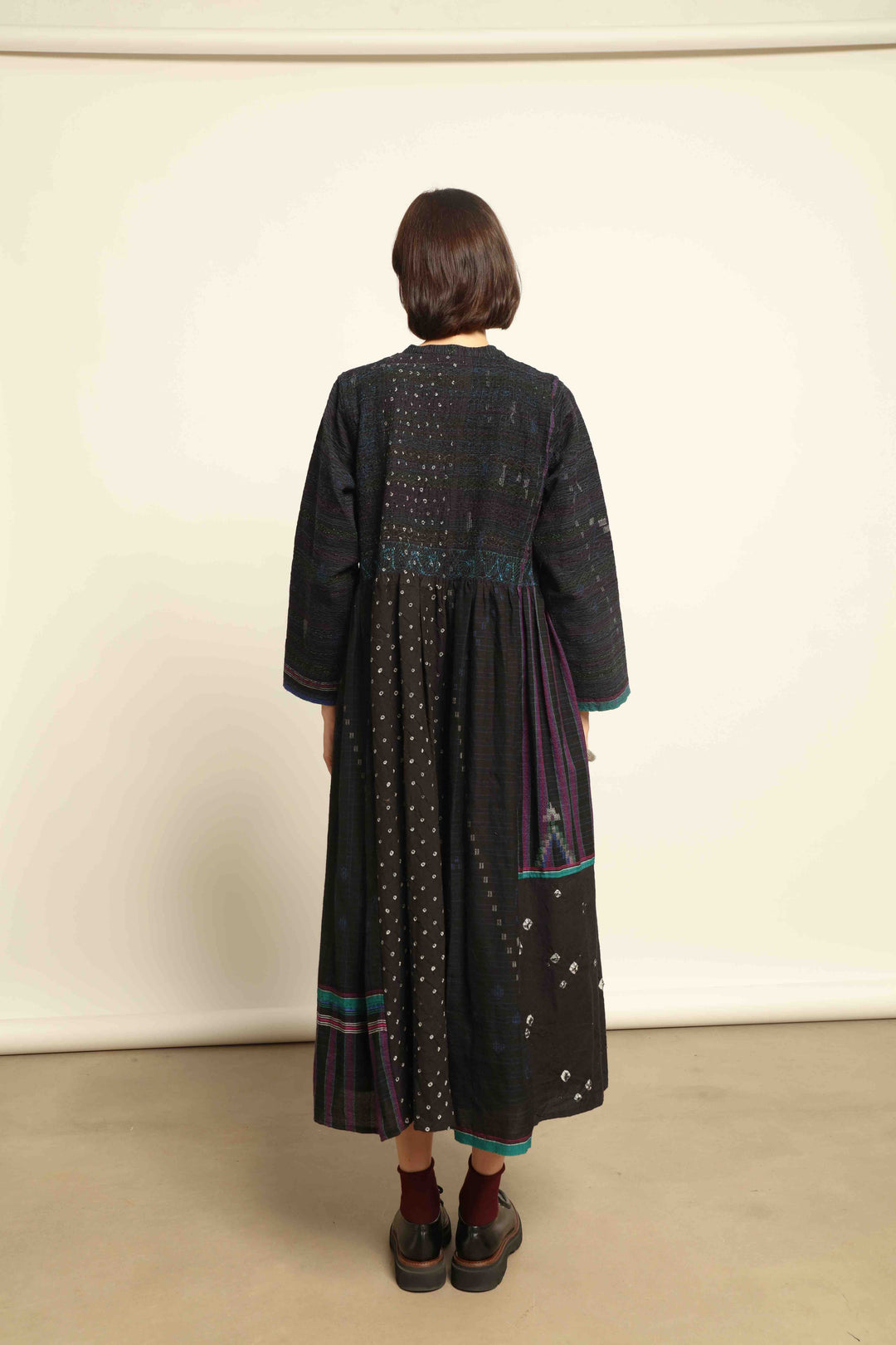 Model is wearing the Folklore 20 dress by Injiri, handmade from silk and wool using traditional Indian handloom techniques, featuring a round neckline, long sleeves, side pockets, and a flattering cut below the bust, curated by House of Nomad Stories.