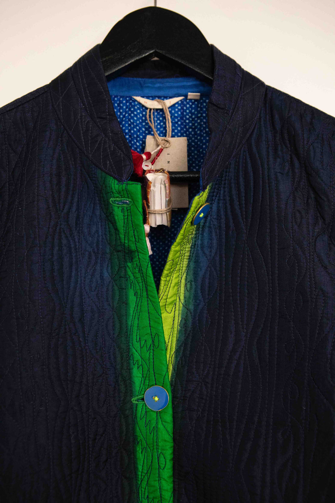Model is wearing the Folklore 18 handmade silk coat by Injiri, featuring a navy blue exterior, green lining, 100% silk, and luxurious artisan craftsmanship.