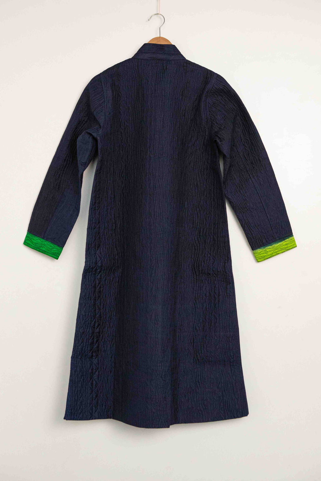 Model is wearing the Folklore 18 handmade silk coat by Injiri, featuring a navy blue exterior, green lining, 100% silk, and luxurious artisan craftsmanship.