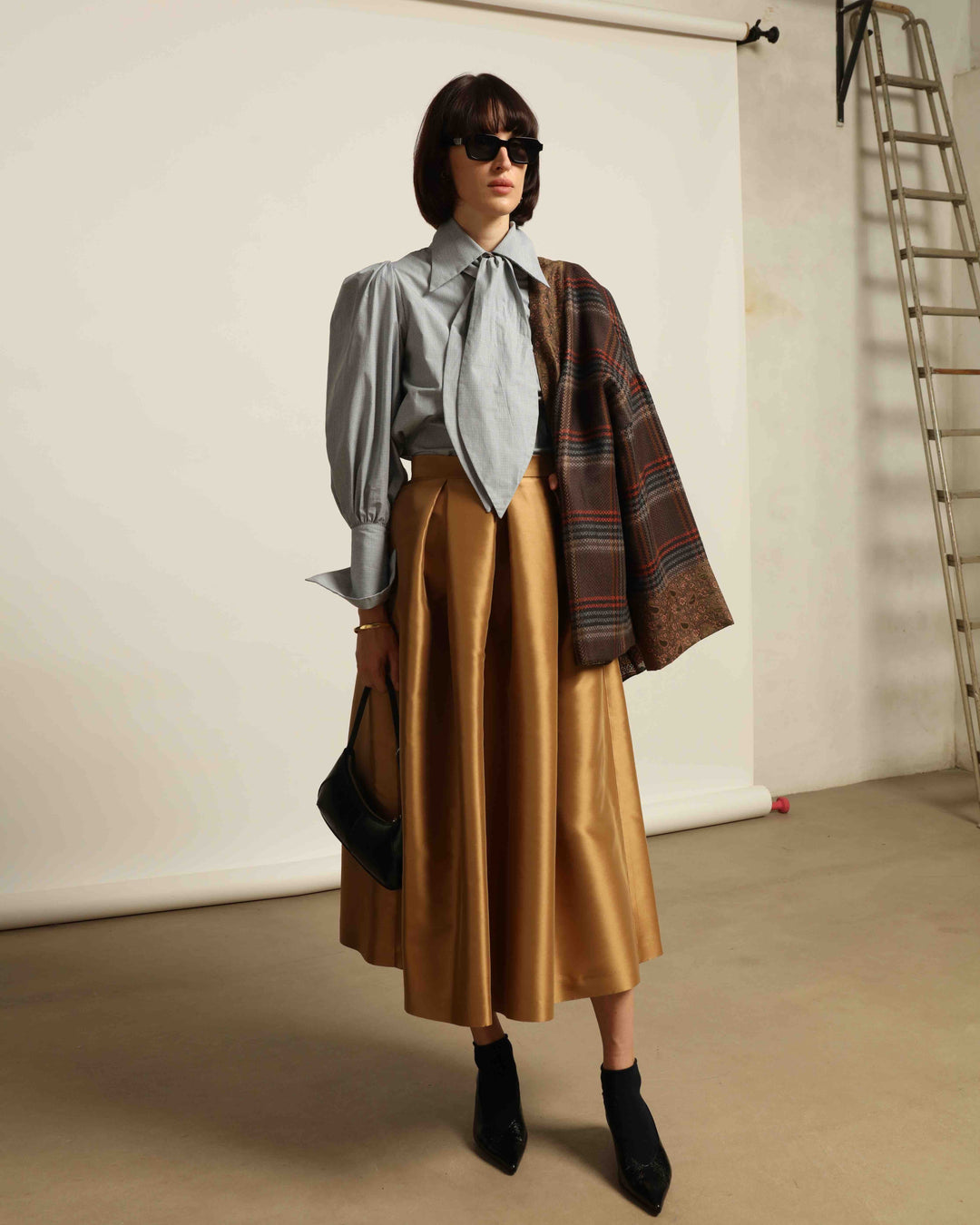 Model is wearing the Karin Micro Check Vichy Cotton Shirt by House of Woven Stories, featuring puffed sleeves, a detachable tie, and a timeless checked design, handmade in Italy from 100% organic cotton.