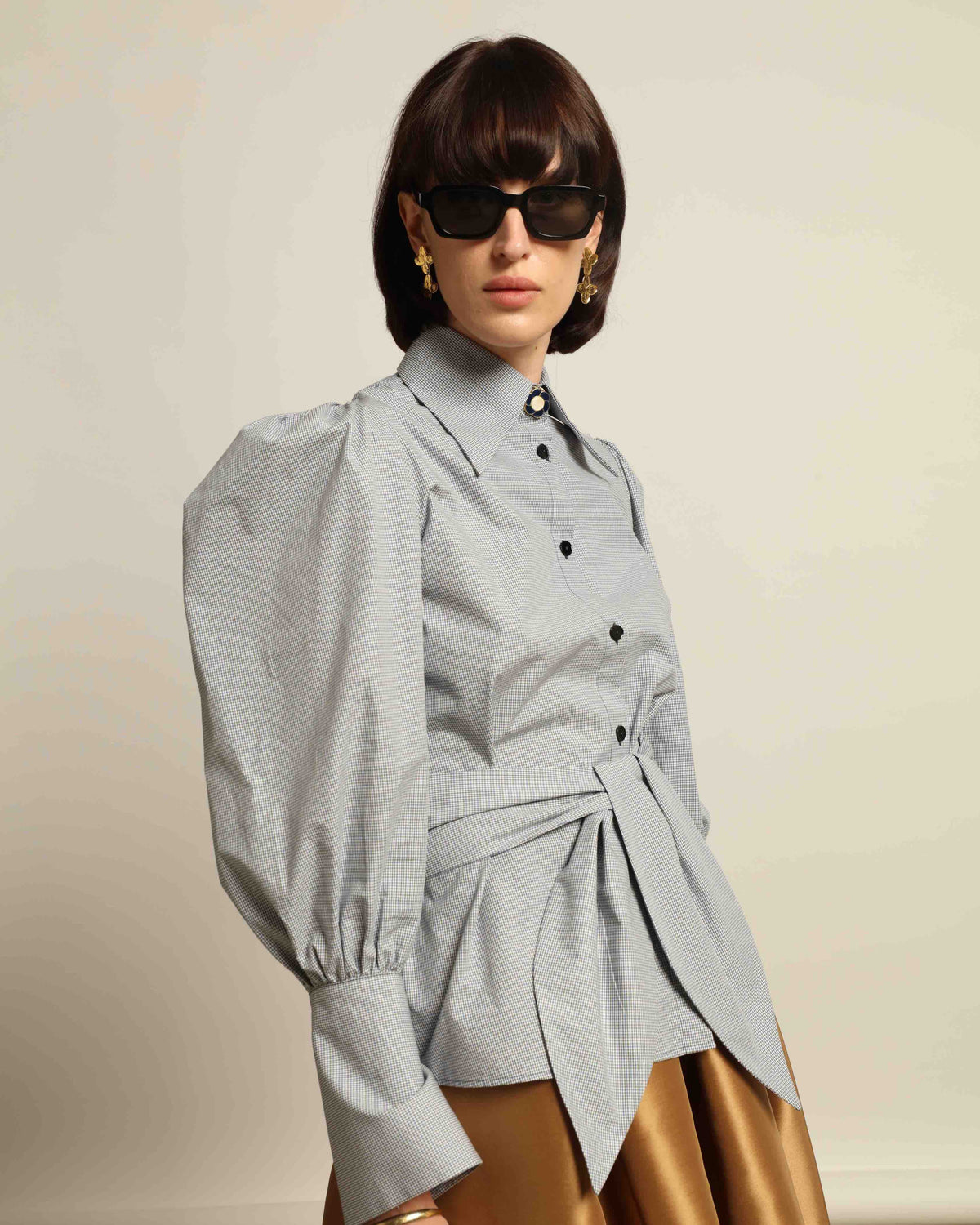 Model is wearing the Karin Micro Check Vichy Cotton Shirt by House of Woven Stories, featuring puffed sleeves, a detachable tie, and a timeless checked design, handmade in Italy from 100% organic cotton.
