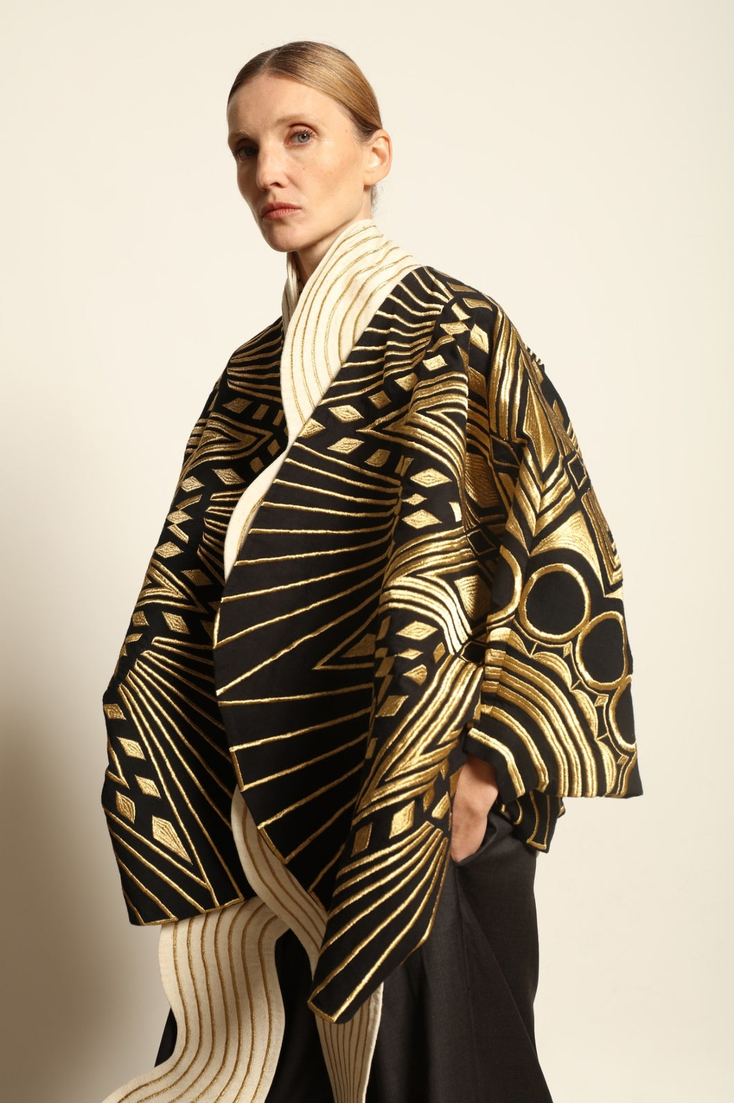Model is wearing the Sunhera Reversible Jacket by Ka-Sha, a handcrafted cotton piece with rich gold stitching, offering two looks — black and gold or beige and gold — crafted over 65 hours and curated in the House of Woven Stories selection.