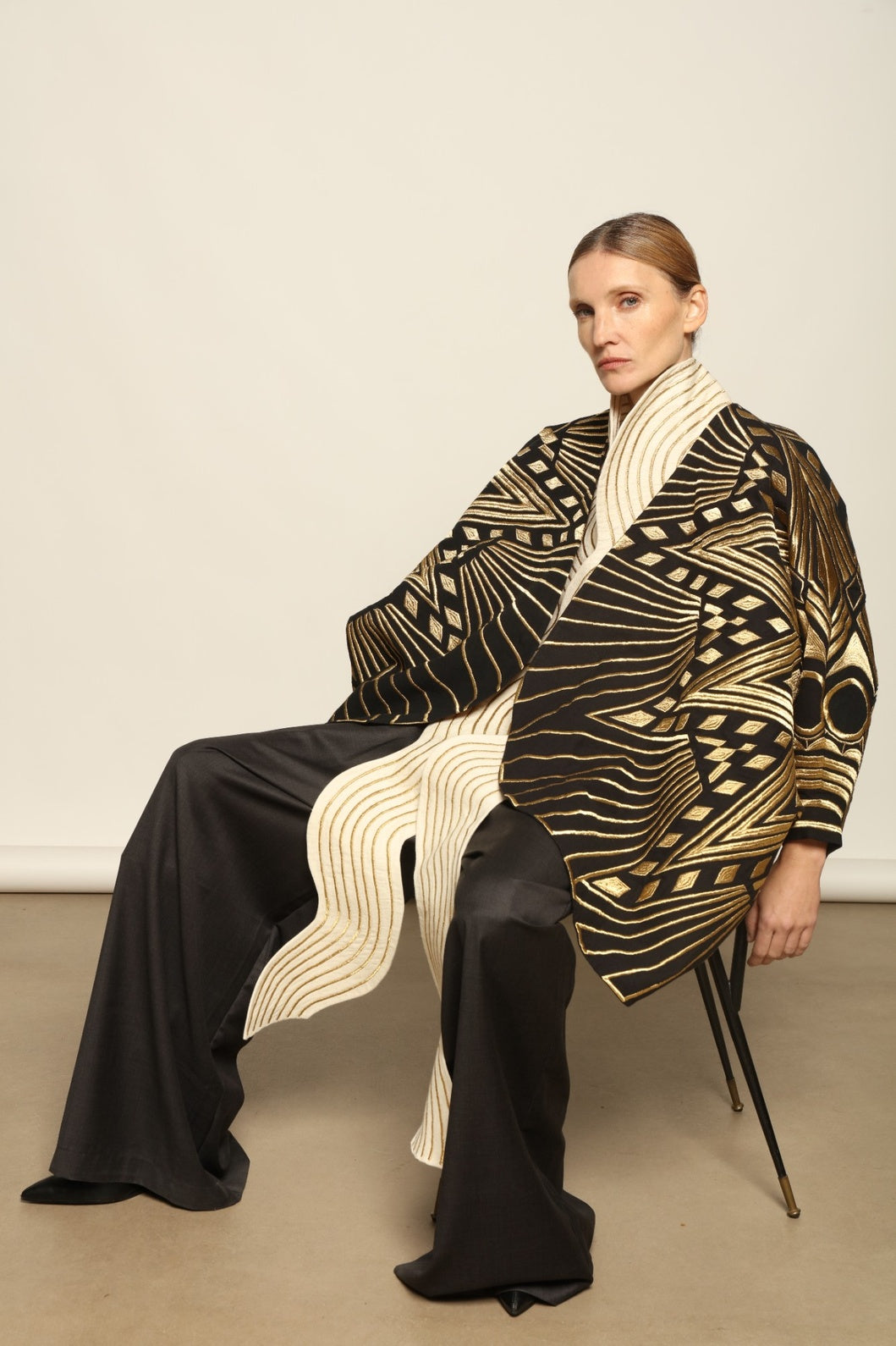 Model is wearing the Sunhera Reversible Jacket by Ka-Sha, a handcrafted cotton piece with rich gold stitching, offering two looks — black and gold or beige and gold — crafted over 65 hours and curated in the House of Woven Stories selection.