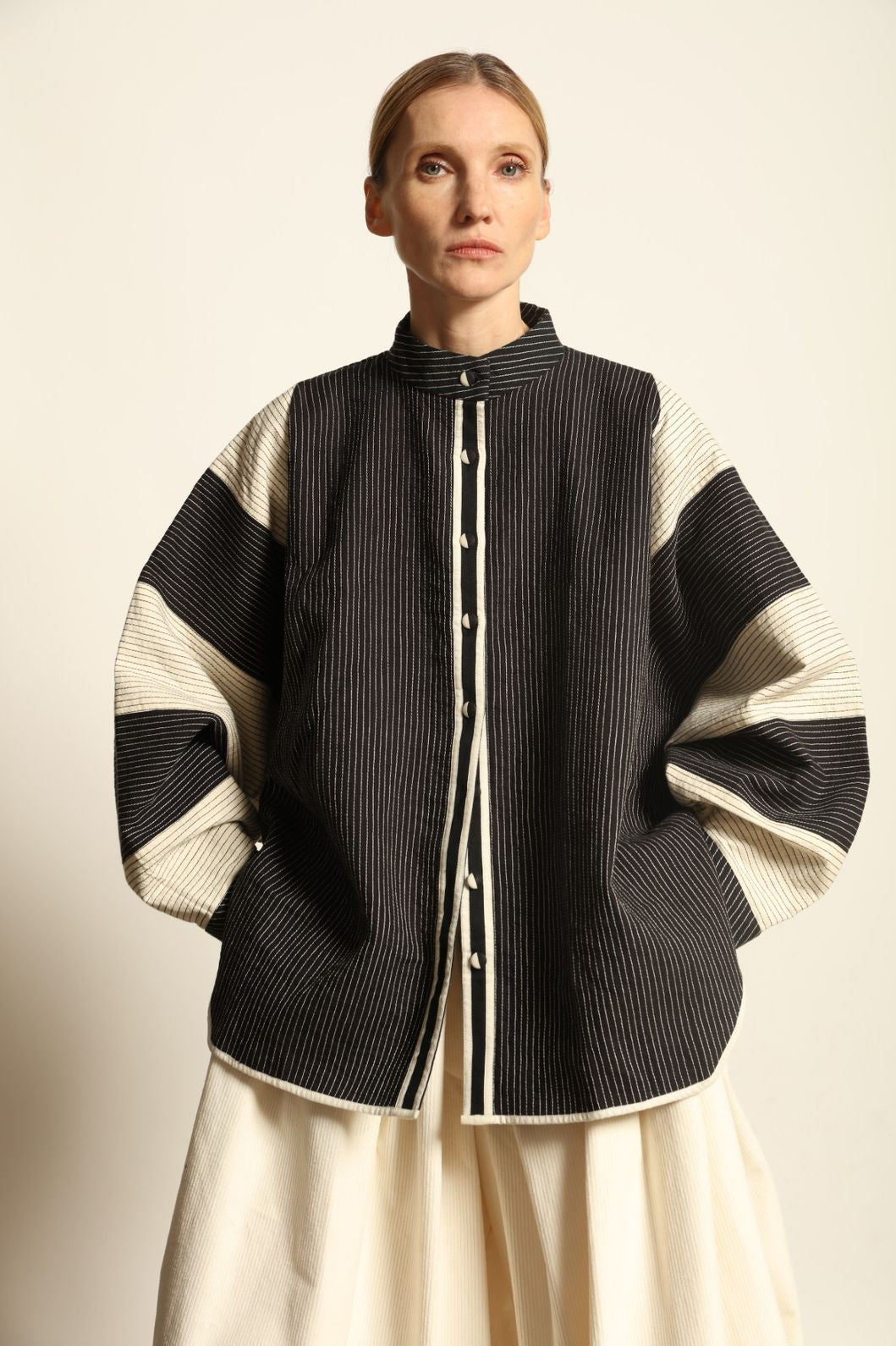 Model is wearing the Tri Bat Reversible Jacket by Ka-Sha, an artisanal reversible cotton jacket with bold black-and-white panels and wide sculptural sleeves, curated in the House of Woven Stories selection.