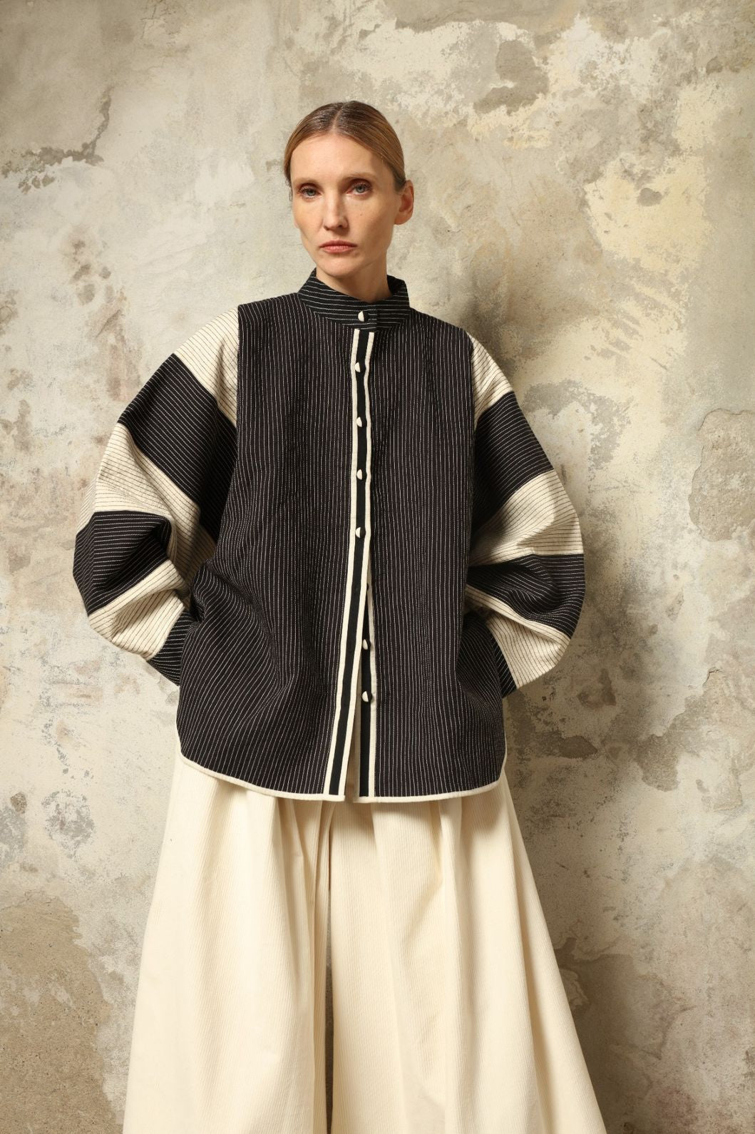 Model is wearing the Tri Bat Reversible Jacket by Ka-Sha, an artisanal reversible cotton jacket with bold black-and-white panels and wide sculptural sleeves, curated in the House of Woven Stories selection.