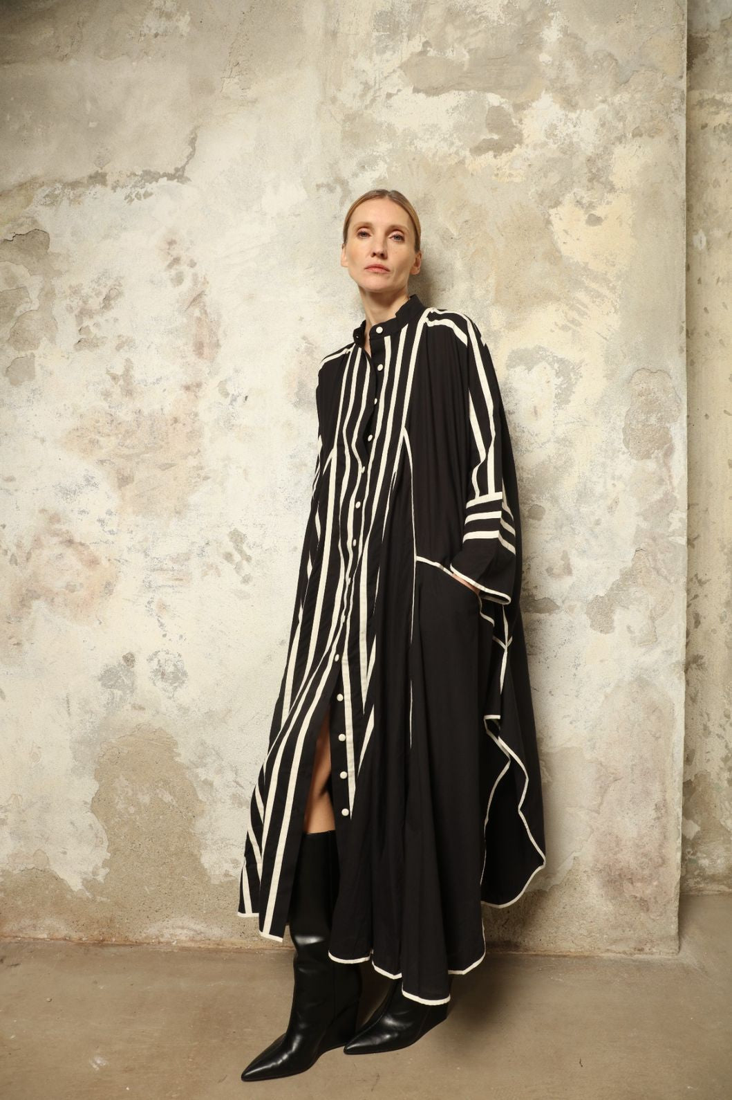 Model is wearing the Vibhor Tunic by Ka-Sha, a handcrafted black cotton tunic with off-white stripes, flowing sleeves and button-down front, curated in the House of Woven Stories selection.