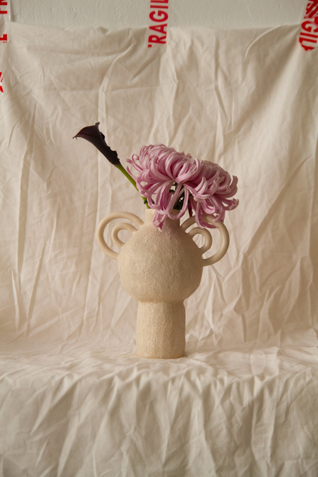 L’Enfant Lune aux Doubles Anses by Clandestine Céramique, handbuilt in sandy clay with double curving handles and soft glaze, part of the House of Nomad Stories selection.