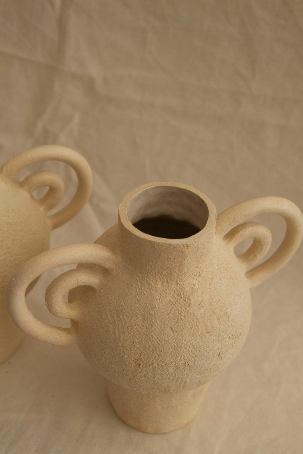 L’Enfant Lune aux Doubles Anses by Clandestine Céramique, handbuilt in sandy clay with double curving handles and soft glaze, part of the House of Nomad Stories selection.