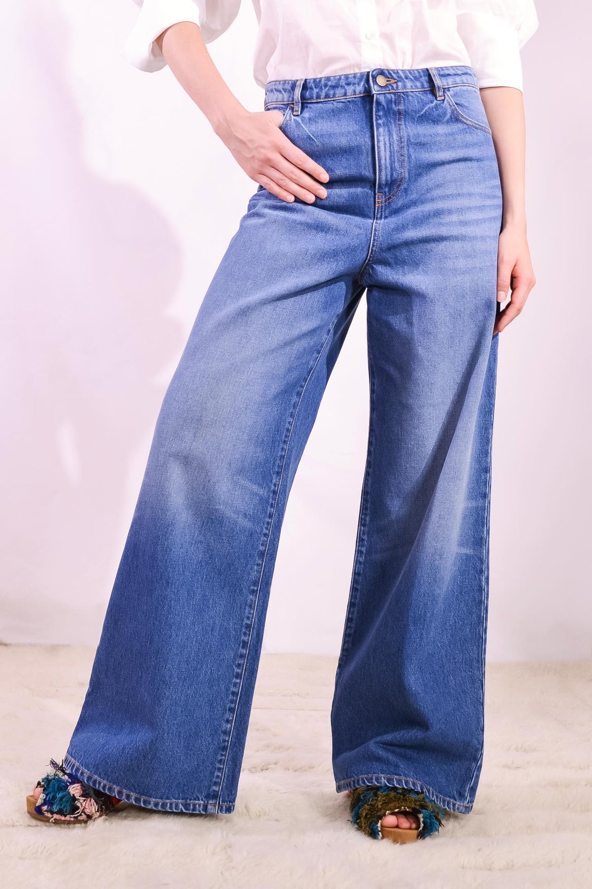 Model is wearing the Le Pantalon Baggy in Bleu d’Été Vintage by Happy Haus - relaxed boyfriend-style recycled denim jeans with wooden button, flower-shaped back pockets, and tobacco-colored topstitching.