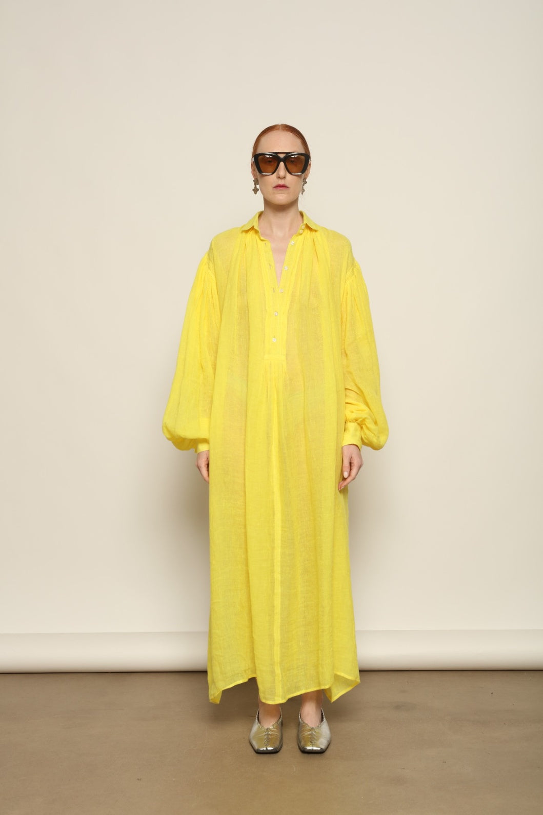 Model is wearing the Les Vacances d’Irina Carmen Linen Dress in Yellow, handcrafted from linen with dramatic wide sleeves, from the House of Nomad Stories selection.