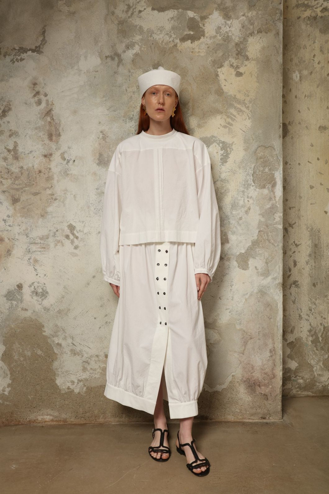 Model is wearing the Les Vacances d’Irina Jade white cotton skirt with high waist and double-breasted button front, from the House of Nomad Stories selection.