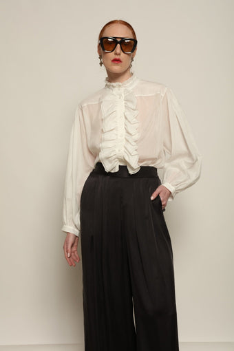 Model is wearing the Les Vacances d’Irina Victorian White Blouse with ruffled collar, front frills and voluminous sleeves, handcrafted in Bucharest, from the House of Nomad Stories selection.