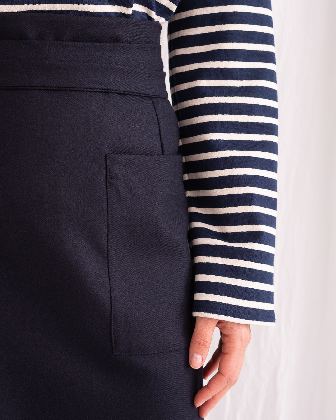 Model is wearing the Wrapped Wool Skirt by Les Vacances d’Irina, a mid-length dark-navy handmade wool skirt with fluid wrap design, available at House of Woven Stories.